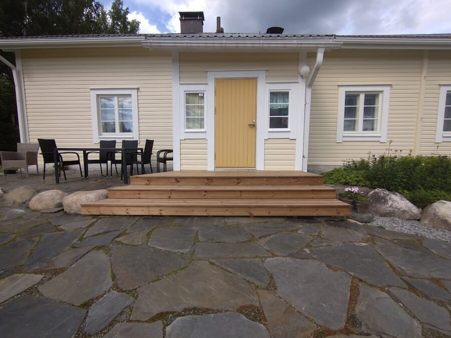 Tumma liuskekiveys mökin edustalle.
